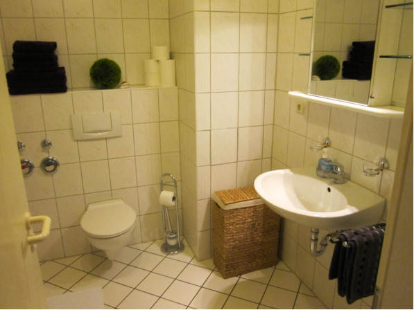 Badewanne, Dusche, Waschbecken und WC sowie einen Spielgelschrank. Duschabtrennung mit Schiebetüren.